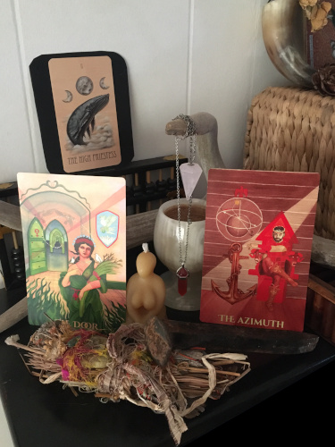 The Empress and Emperor tarot cards atop an altar of crystals, stones and other items..