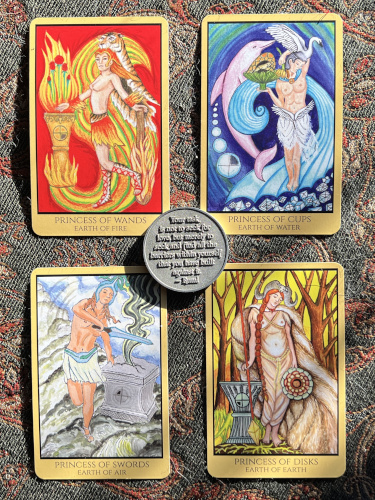 The four Princess tarot cards laying on a table beneath a sacred coin.