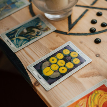 Four tarot cards on a table along with rune stones.