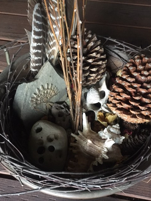 Earthly Taurus related objects: pinecones, shells, feathers, sticks, rocks and bones in a clay bowl.